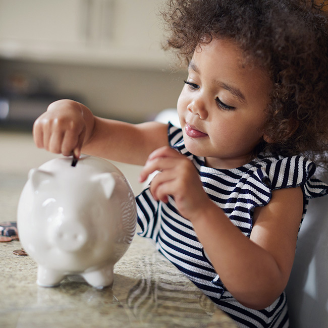 Child putting money in piggy bank