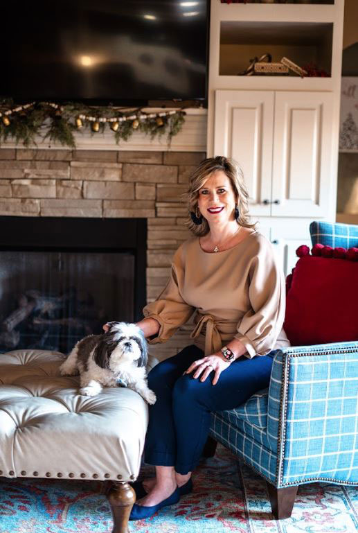 Deena London siting on blue chair with her dog on an ottoman.