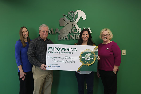 Four people holding scholarship cardboard check